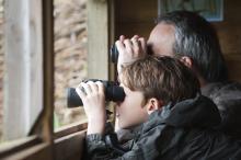 Zwei Personen schauen mit dem Fernglas aus dem Fenster